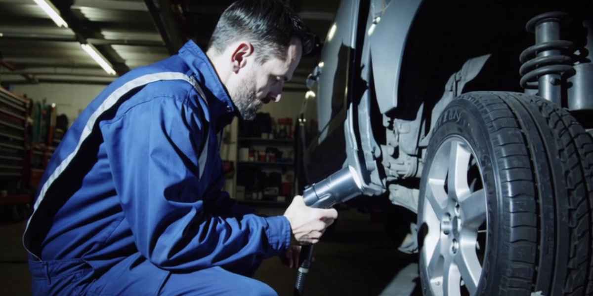 man finding gps tracker on car wheels